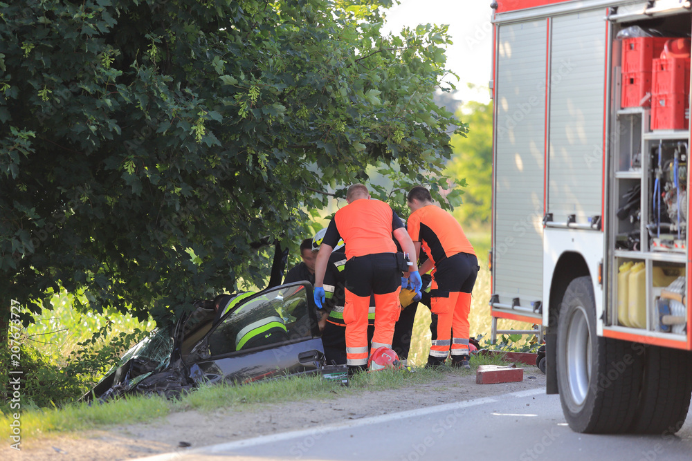 Wypadek samochodu, ratownicy pogotowia i strażacy ratują kierowcę z rozbitego auta. - obrazy, fototapety, plakaty 