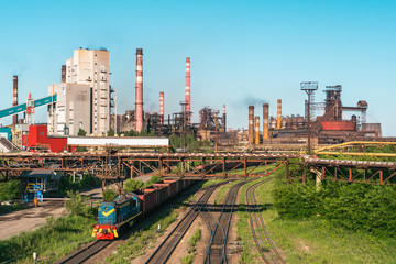 Wall Mural - Cargo freight train wagons go on railroad in industrial zone with plants and manufacturing factories of heavy industry