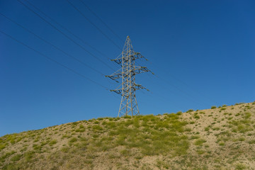 electric tower on a hill against a blue sky.