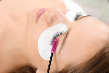 Sticker - Young woman undergoing eyelash extensions procedure, closeup