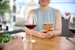 © New Africa - Young woman with smartphone and glass of wine at table