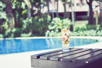 A glass of water juice on swimming pool in vacation and summer time.