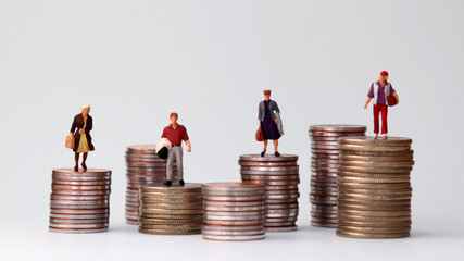 Wall Mural - Miniature people standing on piles of different heights of coins. The growing concept of income gap.