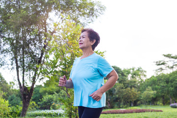 Senior Asian woman have happiness and have wellbeing life by exercise with freshness in the park, maintaining the health of an elderly woman in retirement concept.