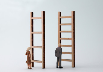 Wall Mural - Miniature men and women standing in front of different ladders. The standard concepts that are discriminatory against men and women in their work.