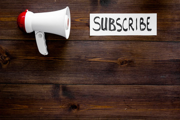 Poster - Subscribe template or mockup. Hand lettering subcribe near megaphone on dark wooden background top view space for text