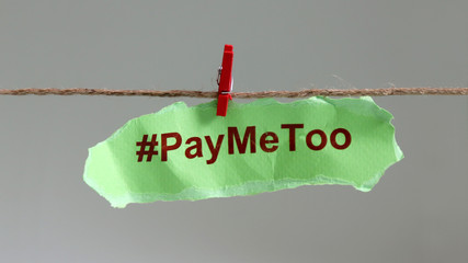 Wall Mural - #PayMeToo as a new social movement. A piece of paper with #PayMeToo written hanging on a clothesline.