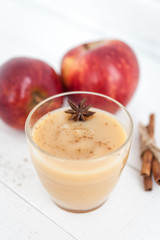 Apple sauce, puree in a glass with spices on a white wooden table  