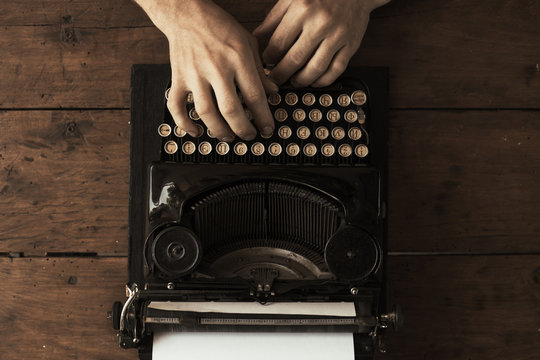 Young man's hands typing on an antique vintage typewriter
