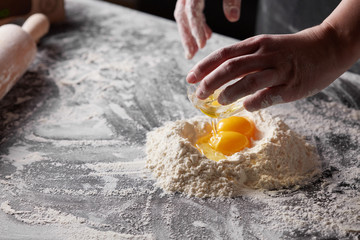 Wall Mural - women's hands is cooking dough for baking on a kitchen table.