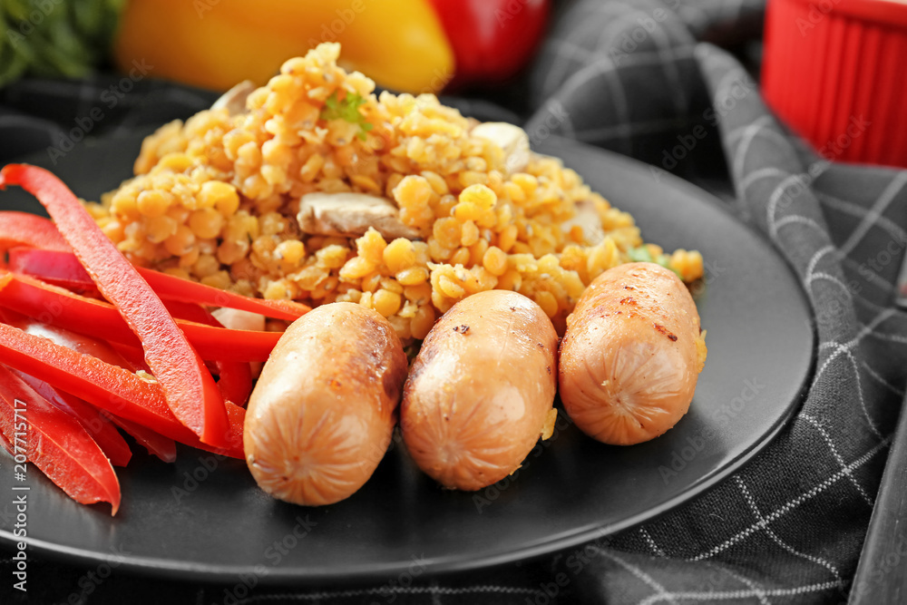 Plate with tasty lentils, sausages and vegetables on table