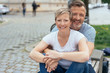 © contrastwerkstatt - Happy middle-aged couple sitting on an urban bench