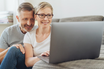 Affectionate middle-aged couple using at a laptop