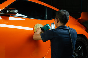 Canvas Print - Car detailing series: Polishing orange sports car spoiler door