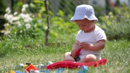 Wall Mural - Little baby boy, playing with big construction blocks in garden, building different shapes