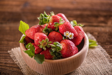 strawberries in wooden bowl on wood table