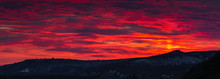 Beautiful Panoramic HDR Scene Of Late Sunset With Red Skies Over Darken Ground And Some Silhouettes Chalk Hills In The Far Background