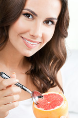 Wall Mural - Smiling woman eating grapefruit at home