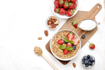 Wall Mural - Serving option of granola bowl with mix of nuts, cereals, fruits and berries, greek yogurt. Healthy vegetarian breakfast, organic strawberry, blueberry, mint, almond. Close up, top view, background.