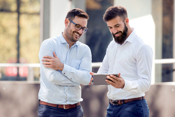 two business people outside looking tablet