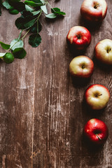 Wall Mural - flat lay with arranged ripe apples and green leaves on wooden tabletop