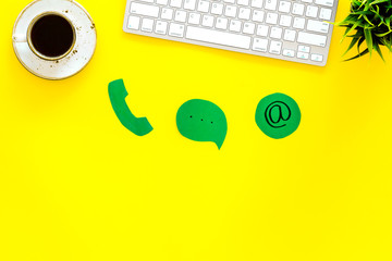 Poster - Customer service concept. Concact information. Phone, message, email signs on office work desk with computer on yellow background top view copy space