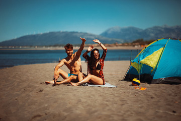 Wall Mural - Young happy couple camping on the beach during the summer