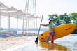 © sanechka - Happy woman is standing with a SUP board in his hands