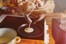Cooking pancakes. In kitchen on a round skillet liquid dough from the ladle is poured
