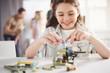 © Yakobchuk Olena - Portrait of satisfied little lady making helicopter from constructor while locating at table during lesson