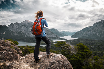 tourist hiker with red backpack takes pictures of the valley with mountains and lakes. patagonia, ar