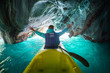 Woman sits in kayak with rised hands inside the Marble Cave on the lake of General Carrera, Chile