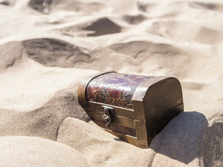 locked treasure case buried in sand on the beach