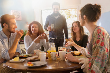 Wall Mural - bunch of multi-ethnic friends gathered around a table for breakf