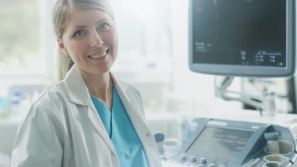 Wall Mural - In the Hospital, Professional Female Obstetricians, Works with  Ultrasound Control Panel, Turns around and Smiles on Camera.  Shot on RED EPIC-W 8K Helium Cinema Camera.