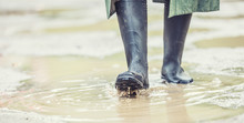 A Man With Black Boots Walks On A Flooded Road