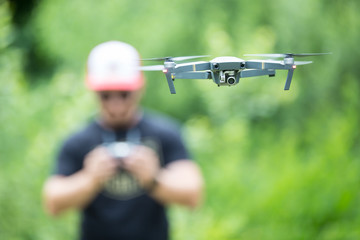 Young man holding remote controller and flying with drone in the park