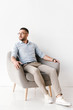 © Drobot Dean - Full length portrait of businesslike man wearing stylish formal clothing sitting in armchair and looking aside, isolated over white background