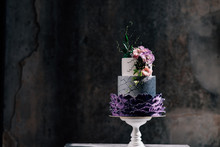 Closeup Of White Wedding Cake With Flowers On Top. Cake On The Cake-shelf. White Milk Cream. Cake Decorated With Pink And Purple Flowers