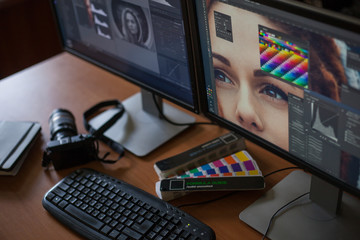 Desktop with two monitors, a keyboard, a camera, a diary, a palette for a designer, a retoucher, a photographer. With the image of the model on the monitors in special programs for retouching.