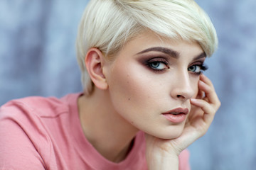 Portrait of young female model in fashionable make up with short hair looking at camera