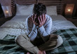 © TheVisualsYouNeed - indoors portrait of young desperate and depressed man at home bedroom sitting on bed sad and confused suffering pain and depression crying lost