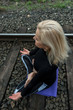 Attractive senior blond woman, dressed in black, doing yoga poses outdoor on railroad. Concept: on the right path. 