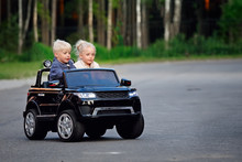 Boy And Girl On Toy Electric Car