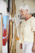 © Monkey Business - Senior Woman Looking At Paintings In Art Gallery