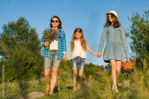 Fotografia, Obraz Mother and daughter hold hands, walk along the country road.