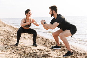 Canvas Print - Happy young sport couple doing squats