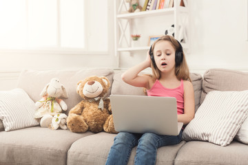 Little girl doing homework on laptop at home