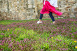 Woman in pink dress walking on meadow full of spring flowers, enjoying nice weather,  fresh air and nature
