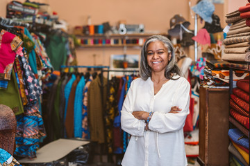 Wall Mural - Mature woman smiling while standing in her fabric shop